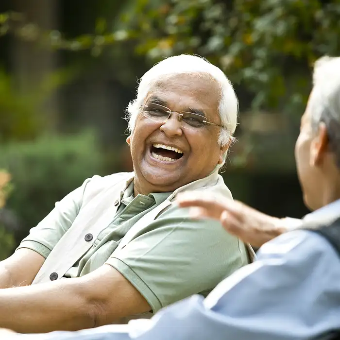 senior man on a bench laughing and smiling with a friend