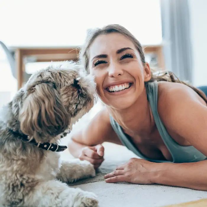 woman being sniffed by a dog and smiling with great teeth