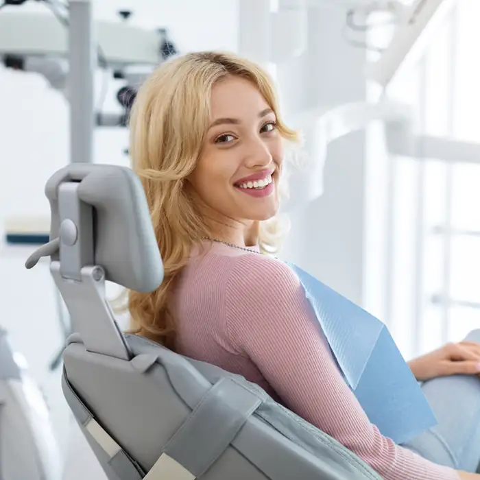 young woman in dentist's chair overlooking her shoulder and smiling