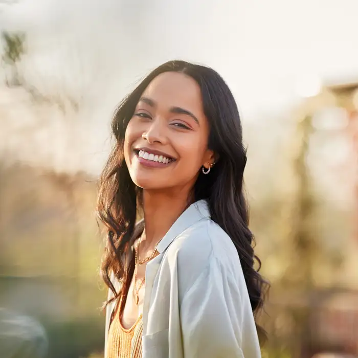 young adult woman outdoors and smiling at the camera