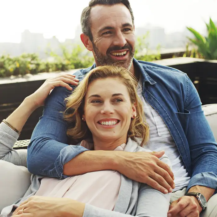 older couple smiling and embracing on patio outdoors overlooking a city