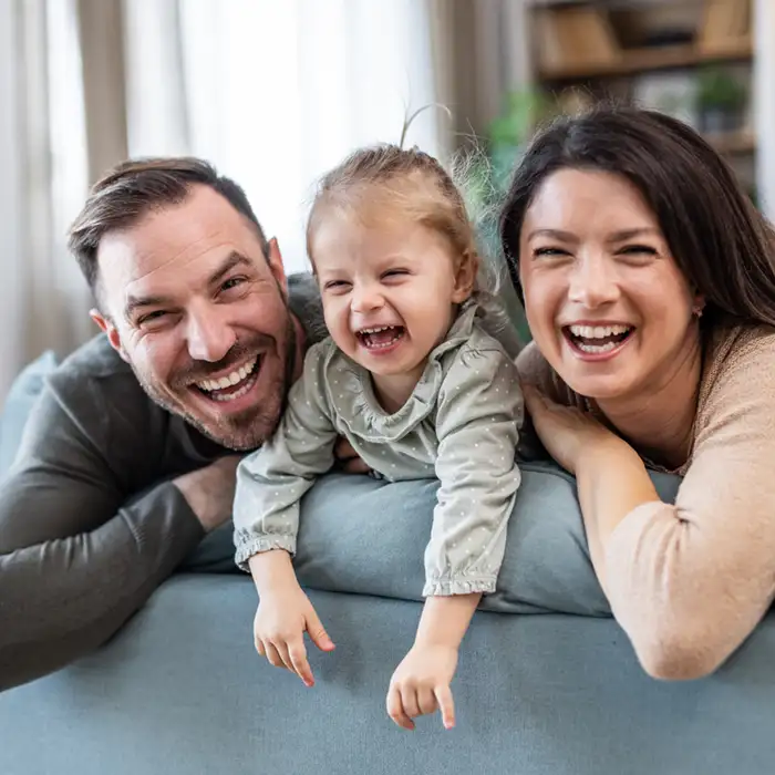mother, father, and young daughter smiling and laughing