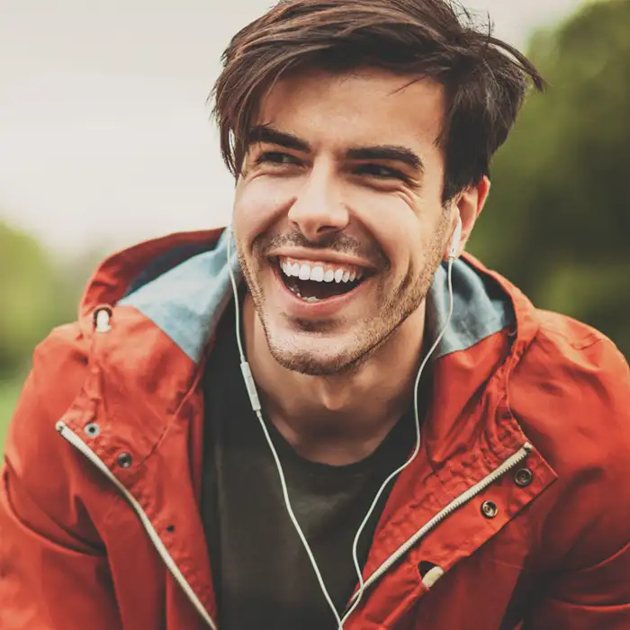 adult man on a hike smiling and listening to music